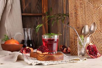 Bowl with fresh pomegranate and glass of juice on white table