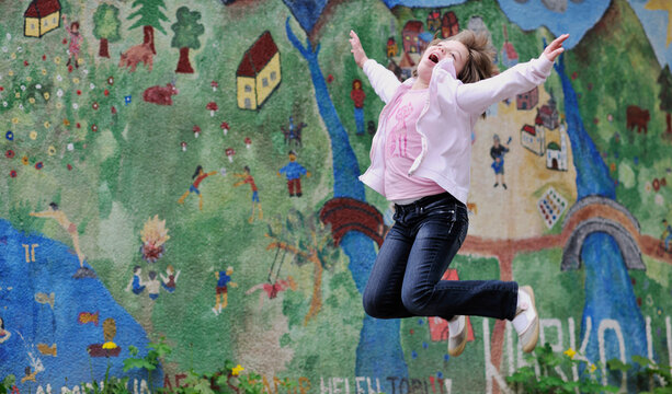 happy young girl posing and jumping with abstract urban style painting bacground begind