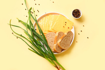 Plate of tasty processed cheese with bread and scallions on orange background