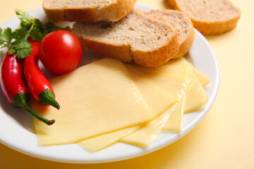 Fototapeta na wymiar Plate of tasty processed cheese with bread and vegetables on yellow background