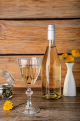 Bottle and glass of dandelion wine on wooden table