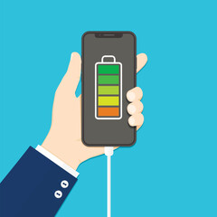 Human hand holding mobile phone with charger connected