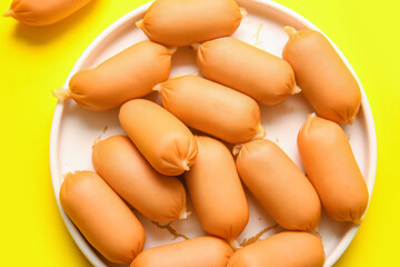 Plate of tasty boiled sausages on yellow background