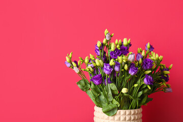 Vase with eustoma flowers on red background