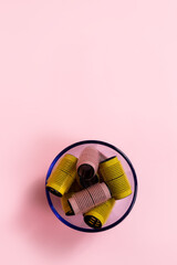 Velcro curlers in a blue glass bowl on pink background
