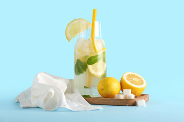 Board and glass with fresh lemonade on blue background