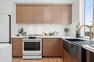 Modern subway tiled Kitchen with brown cabinets and gold accents  