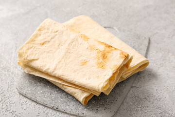 Board with fresh lavash on grey background