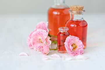 Composition with pure natural organic rose essential oil in glass bottle, luxury perfumery ingredient for premium fragrance, skin care products, anti-age beauty treatment. Fresh flowers