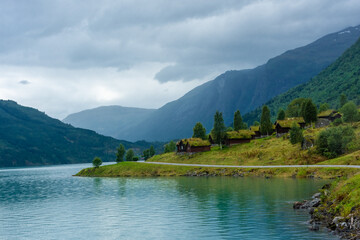 Fototapeta premium Wooden rorbus, typical houses with grass on the roof, on the Lovatnet Lake, Norway