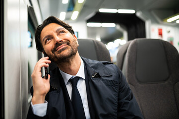 Portrait of a smiling manager on the phone on a train