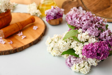 Mortar with beautiful lilac flowers on white table near orange wall