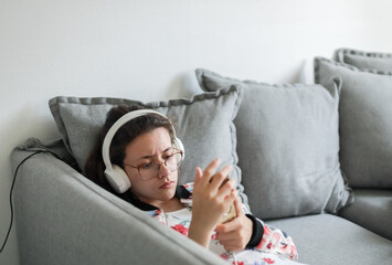 Portrait of a beautiful teenage girl with a phone on the couch.