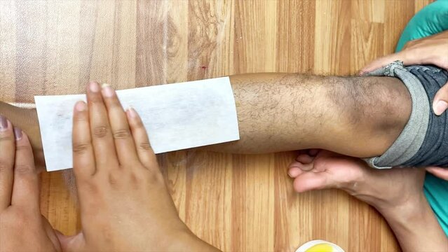 a footage of man's leg getting waxed with honey and sugar. hair removal using sugar honey wax. men hair waxing