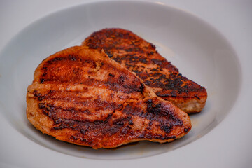 Grilled red tuna steak with pepper macro on a white plate.