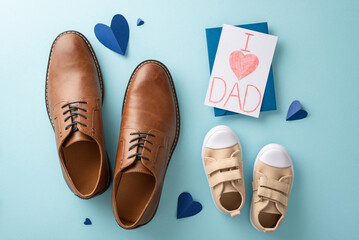 Baby boy surprises dad with heartfelt Father's Day gifts. Top-down view shot of dad's leather shoes, son's sneakers, hearts, handmade postcard, and envelope on pastel blue background
