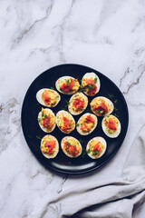Homemade deviled eggs with salmon on a black background.