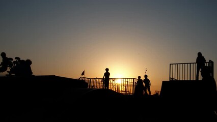 Roller skates on playground during nightfall. Active teens pass free time on roller skates on playground during evening weekend in summer.