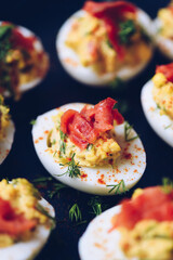 Homemade deviled eggs with salmon on a black background.
