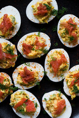 Homemade deviled eggs with salmon on a black background.