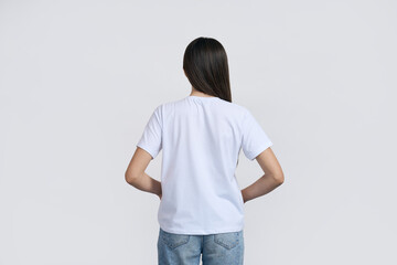 Teen girl in white t-shirt with mockup, standing back to the camera, over white isolated background