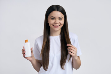 Teenage girl holds white mockup bottle with sunscreen lotion. Sunbathing, skin and body care concept