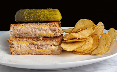   tuna melt sandwich top with pickle  and potato chips,