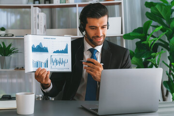 Business man wearing headphone present financial data or BI paper via laptop during online meeting. Remote work concept with virtual meeting presentation of effectiveness remote work. Fervent
