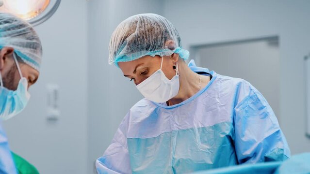 Female obstetrician-gynecologist performing C-section surgery for the pregnant woman. Doctors working in the modern maternity hospital.