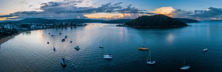 Obraz na płótnie Canvas Aerial sunrise waterscape panorama with scattered rain clouds and boats