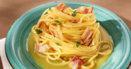 Spaghetti carbonara. Pasta with pancetta, egg, parmesan cheese. Green plate on brown background. Hard light, angle view. Traditional italian cuisine. Pasta alla carbonara.