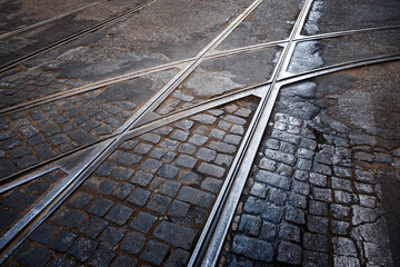 tramway railway crossing on a cobblestone street in lisbon Portugal, with some rain puddles, track junction, urban textures