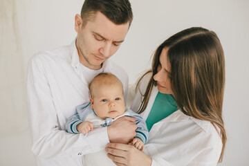 Happy family of mother, father and baby boy, wearing casual clothes on white background.