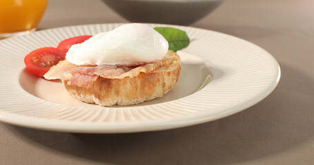 poached egg with bacon on a plate. boiled egg on bread with sauce. delicious breakfast with vegetables. serving food on a sunny day.