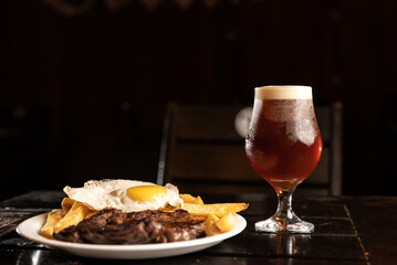 roast beef plate with fried egg and glass of beer in restaurant