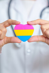 Pansexual Pride Day and LGBT pride month concept. Doctor hand holding pink, yellow and blue heart shape for Lesbian, Gay, Bisexual, Transgender, Queer and Pansexual community