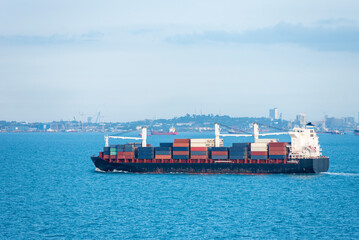 Cargo container ship sailing through peaceful, calm, blue sea on her voyage through the Singapore Strait. 