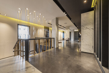 An empty retail space with polished concrete floors and ceiling lighting fixtures and a staircase...