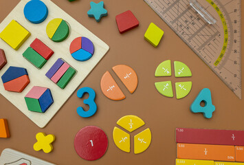 Fractions, rulers, pencils, notepad on brown background. Set of supplies for mathematics and for...