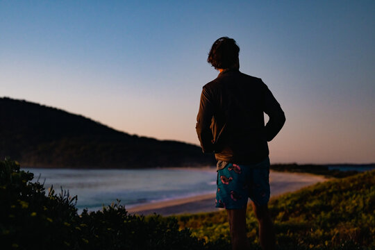 Silhouette image of man standing on Jimmy's Beach early in the morning at Hawks Nest NSW Australia