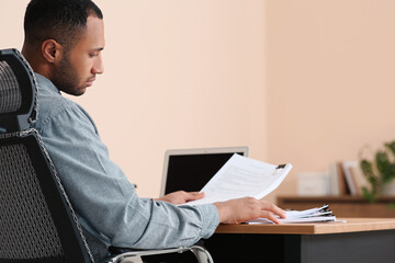 Young businessman working with documents at wooden table in office