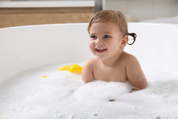 Cute little girl taking foamy bath at home