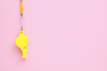 One yellow whistle with orange cord on pink background, top view. Space for text