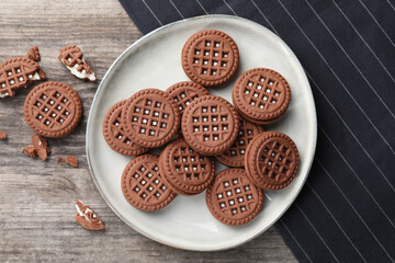 Tasty chocolate sandwich cookies with cream on wooden table, flat lay