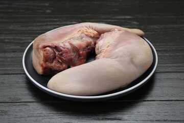 Plate with raw beef tongues on black wooden table, closeup