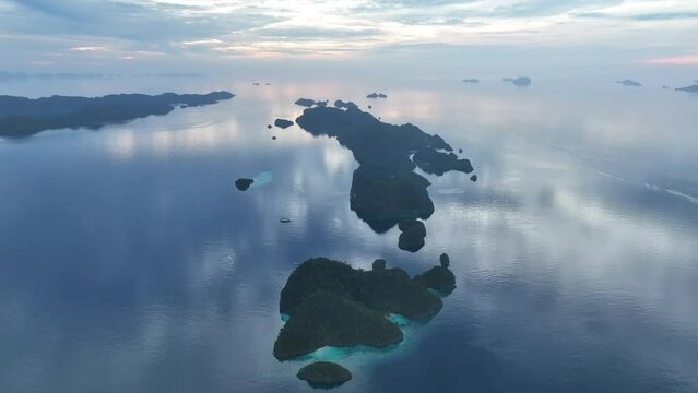 At sunrise, calm seas surround limestone islands that rise from Raja Ampat's dramatic seascape. This remote part of Indonesia is known for its incredibly high marine biodiversity.