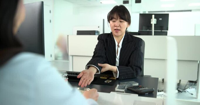 고객에게 미니골드바를 보여주며 설명하는 금거래소 직원