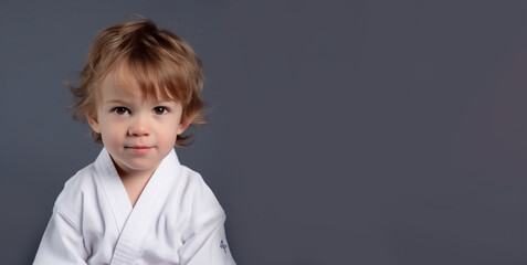 a smiling europe's boy child dressed as a martial arts athletes in soft solid dark grey background generative ai