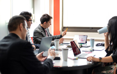 young hispanic mixed group in a coworking space analyzing graphics at the office, work partners coworkers in a meeting room, busy office ambience, businessmen brainstorming