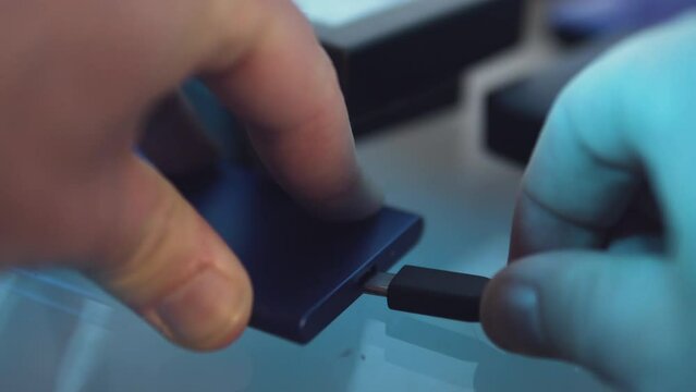 Close up plugging and unplugging a small backup external hard drive solid state disk with type c USB connection. Safe data and big data storage concept.
